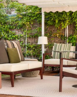 Zona de estar exterior com sofá, poltronas e candeeiro, rodeada por uma parede de plantas/home/klevieco/fontinha.klevie.com
